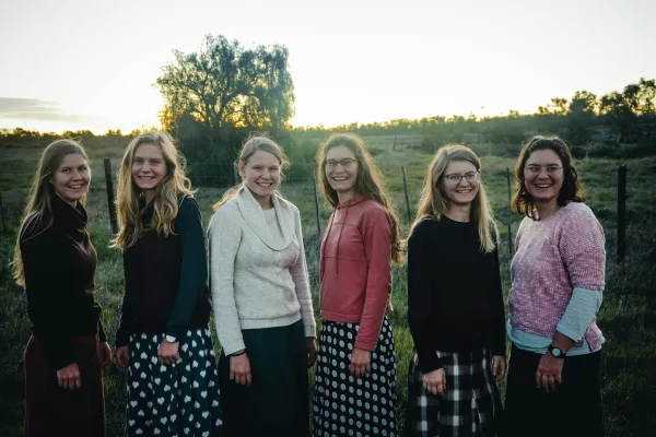 Groupe de jeunes femmes souriantes dans un paysage rural au coucher du soleil