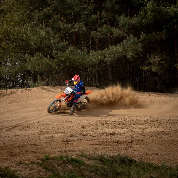 Pilote de motocross en pleine accélération sur une piste sableuse