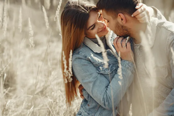 Couple amoureux enlacé dans un champ au coucher du soleil