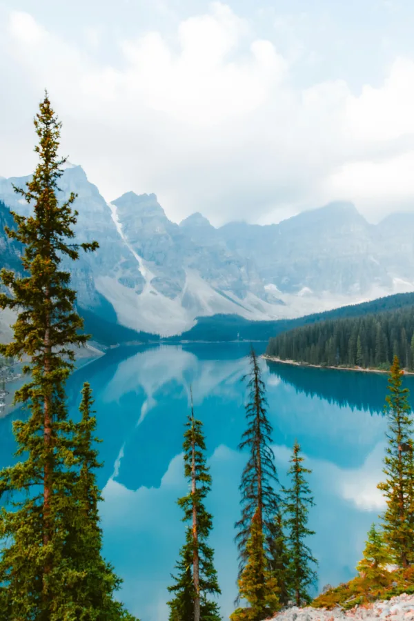 Lac de montagne turquoise entouré de forêts et sommets enneigés
