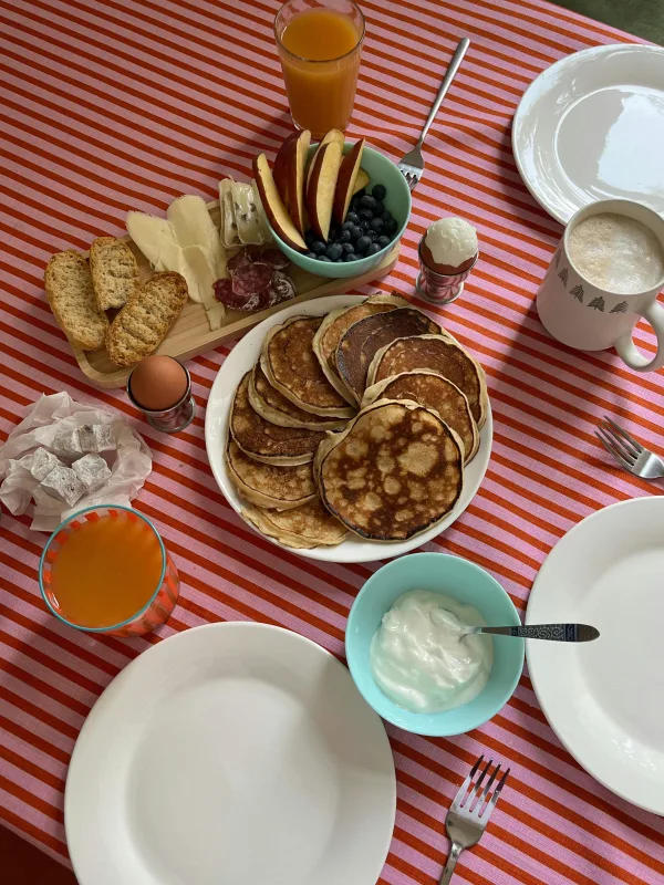 Petit-déjeuner gourmand avec pancakes, fruits et jus d’orange