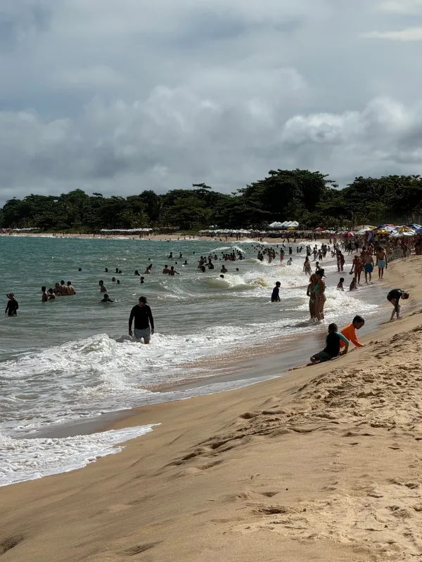 Plage animée avec baigneurs et vagues sous un ciel nuageux