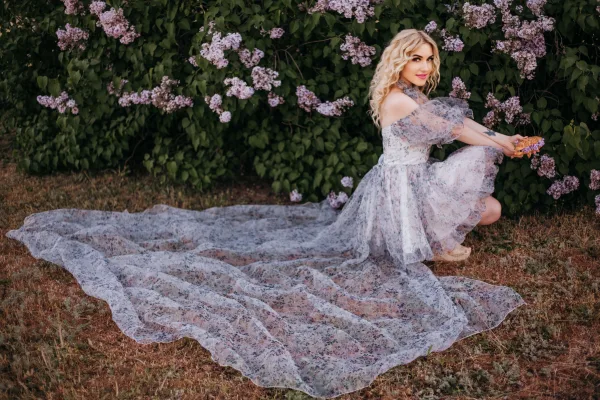 Femme élégante en robe fleurie dans un jardin de lilas
