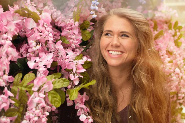 Portrait d’une femme souriante entourée de fleurs roses