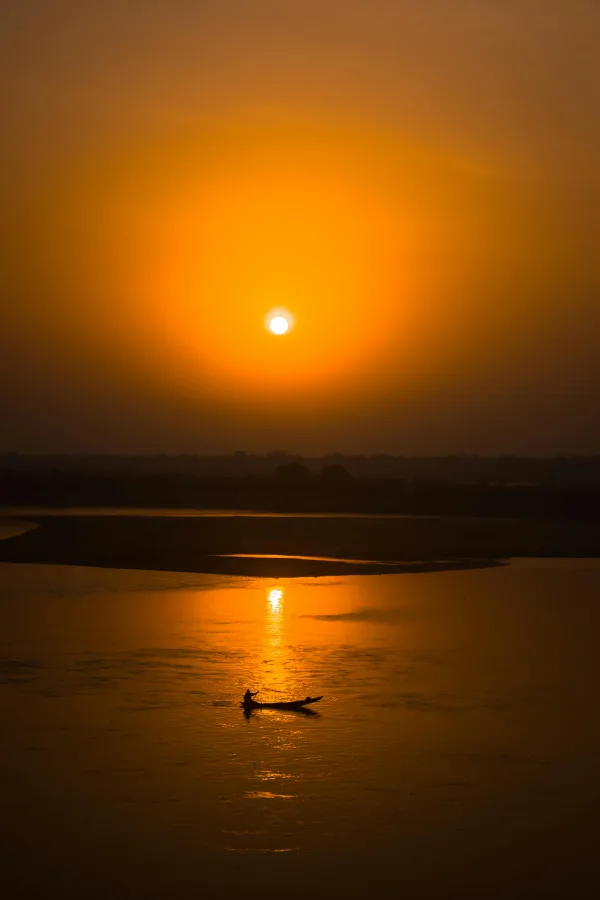 Coucher de soleil doré sur rivière avec silhouette de bateau