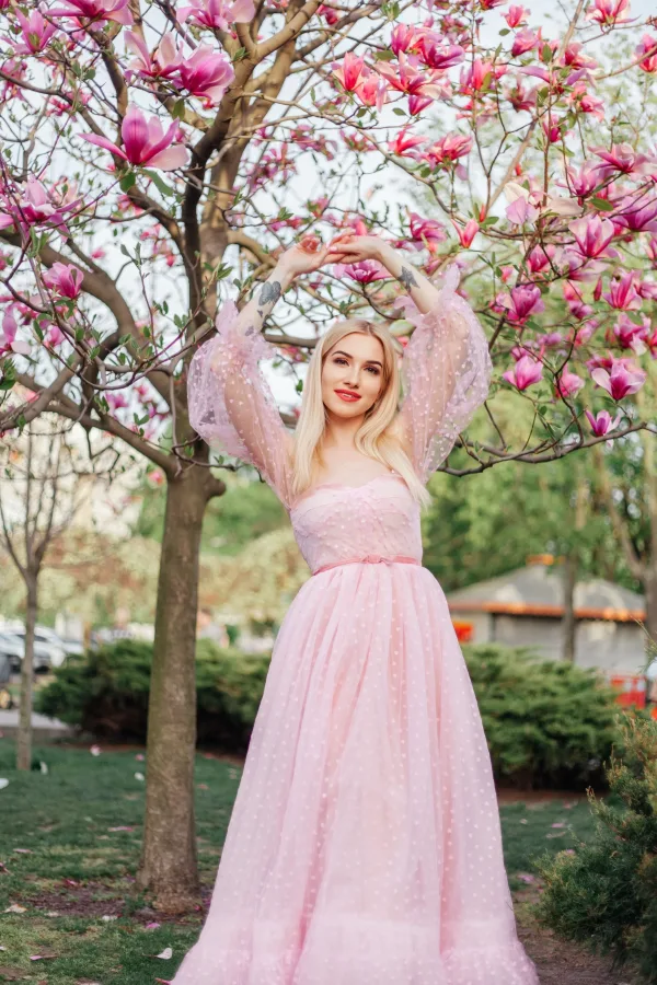 Jeune femme en robe rose sous un magnolia en fleurs