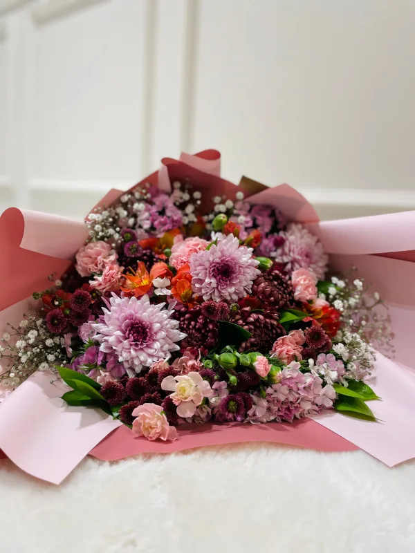 Magnifique bouquet de fleurs colorées emballé dans un papier rose élégant