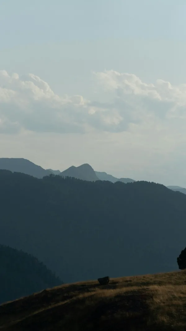 Silhouette de montagnes sous un ciel nuageux au coucher du jour