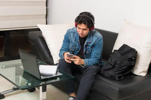 Jeune homme utilisant smartphone et ordinateur portable à la maison