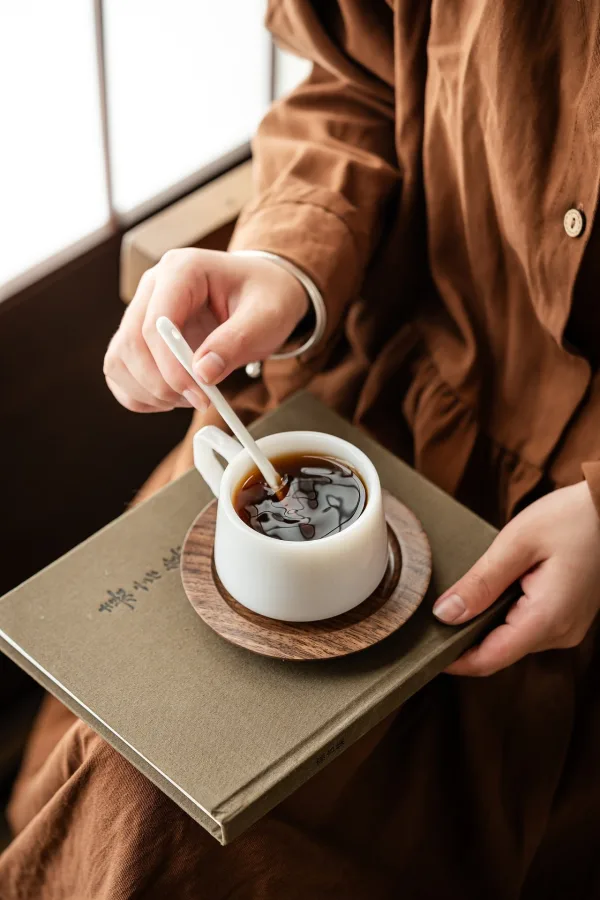 Personne dégustant une tasse de café chaud tout en lisant un livre
