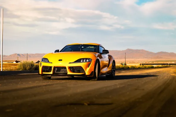 Voiture de sport jaune sur une route désertique au coucher du soleil