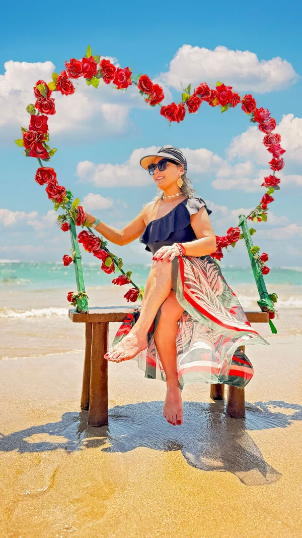 Femme assise sur une balançoire décorée de roses rouges sur la plage