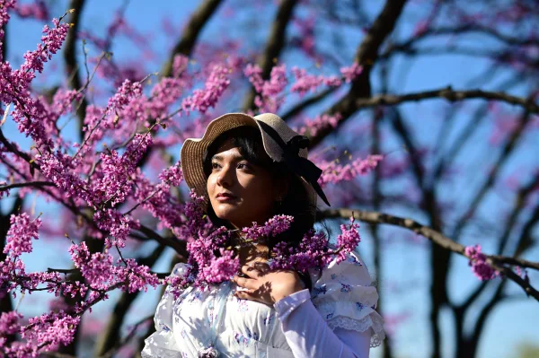 Portrait d’une femme au chapeau entourée de fleurs roses au printemps