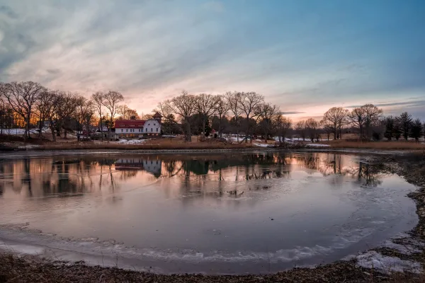 Lac gelé au crépuscule avec reflets d’un village hivernal