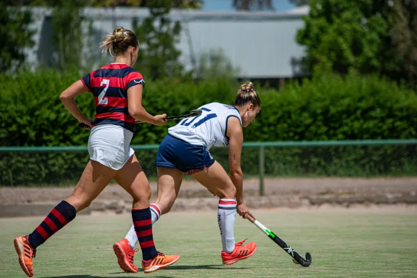 Joueuses de hockey sur gazon en plein match sur terrain extérieur