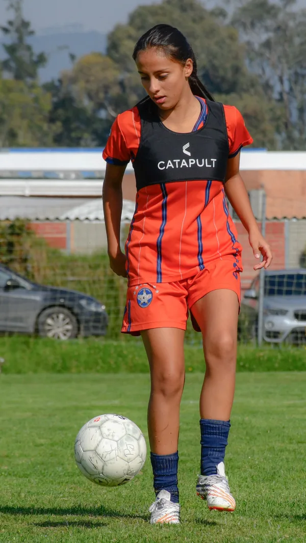 Jeune footballeuse à l'entraînement avec ballon sur un terrain de football