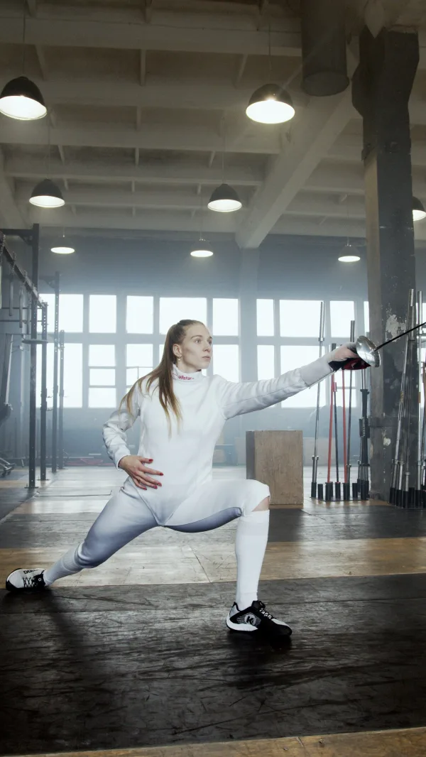 Escrimeuse à l'entraînement réalisant une fente avec son épée