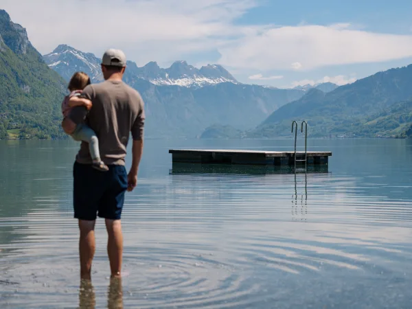 Parent avec enfant au bord d’un lac de montagne panoramique