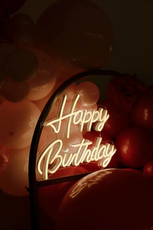 Enseigne lumineuse Happy Birthday entourée de ballons de fête
