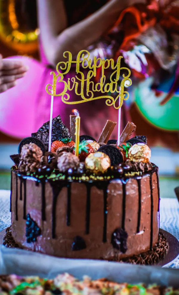 Gâteau d’anniversaire au chocolat avec décorations gourmandes et topper Happy Birthday