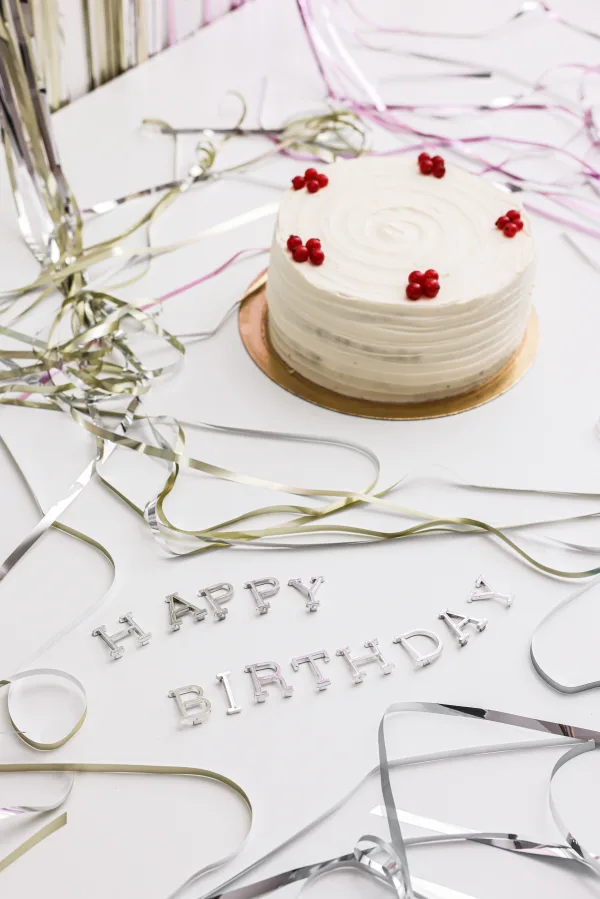 Gâteau d’anniversaire blanc avec décorations festives et rubans argentés