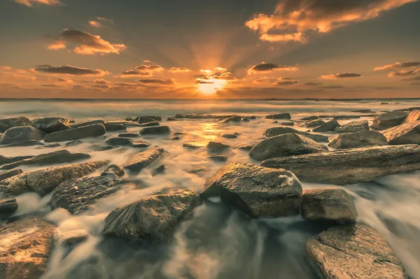 Coucher de soleil sur une plage rocheuse avec vagues en pose longue