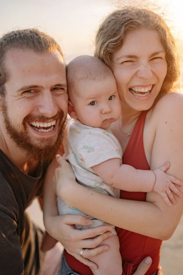 Portrait de famille souriante avec bébé dans les bras au coucher du soleil