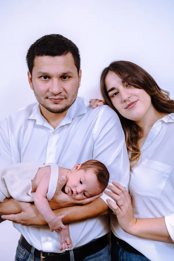 Jeunes parents posant avec leur nouveau-né lors d’un portrait de famille