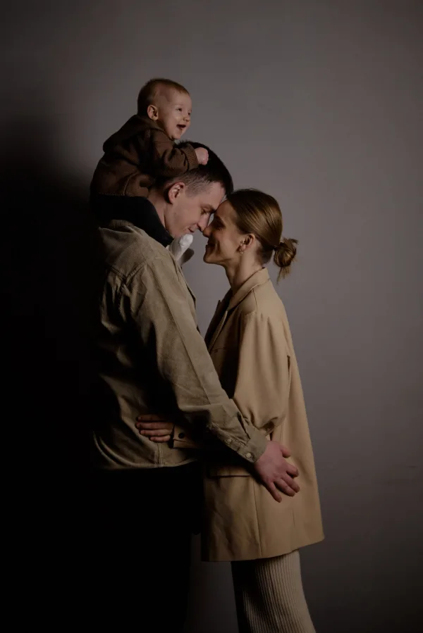 Portrait intimiste d’une jeune famille avec bébé dans un studio minimaliste
