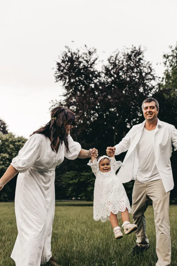 Parents tenant leur petite fille par les mains dans un parc