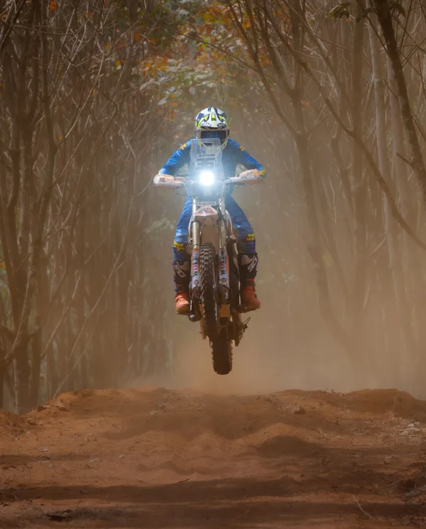 Pilote d’enduro en plein saut sur une moto tout-terrain en forêt