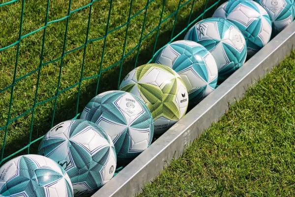 Ballons de football alignés au bord du terrain d'entraînement