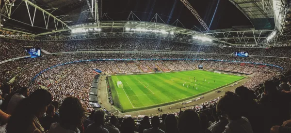 Grand stade de football rempli de supporters lors d'un match en soirée