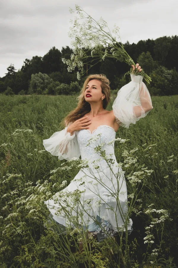 Femme en robe blanche dans une prairie de fleurs sauvages