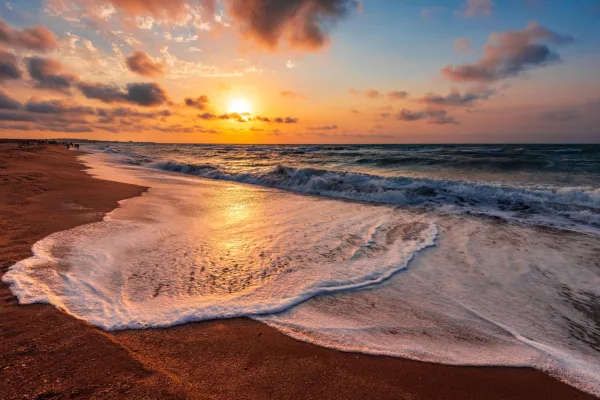 Plage au coucher du soleil avec vagues et reflet doré sur le sable