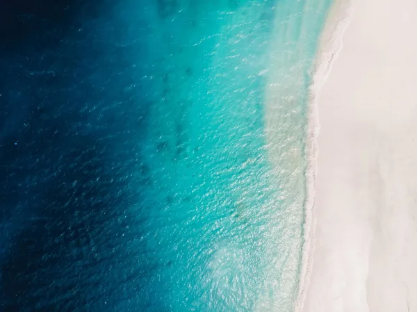 Vue aérienne d'une plage de sable blanc et d'une mer turquoise cristalline