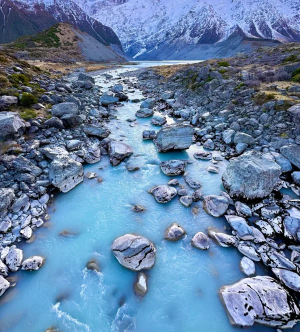 Rivière glaciaire turquoise au cœur d'une vallée de montagnes enneigées