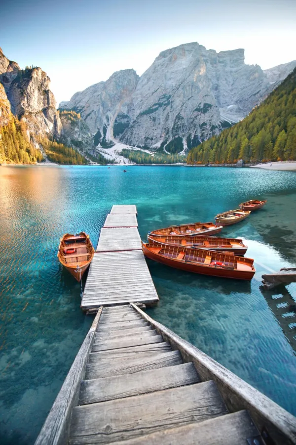Ponton en bois et barques sur un lac de montagne cristallin