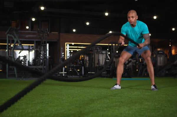 Athlète s'entraînant avec des battle ropes en salle de sport