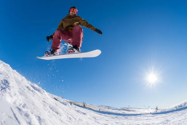 Snowboardeur réalisant un saut spectaculaire sur une piste enneigée