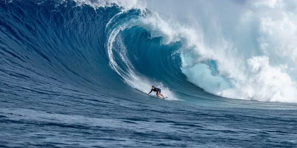 Surfeur affrontant une immense vague en pleine mer