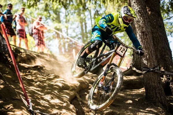 Cycliste de descente VTT en pleine compétition sur un sentier forestier