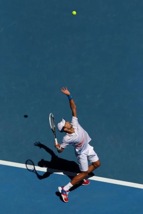 Joueur de tennis exécutant un service vu du dessus sur un court