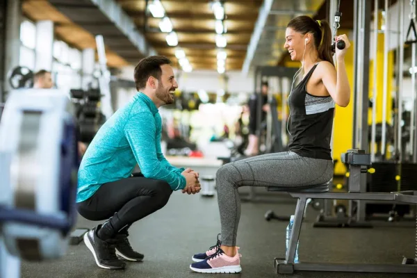 Coach sportif accompagnant une femme pendant une séance de musculation en salle