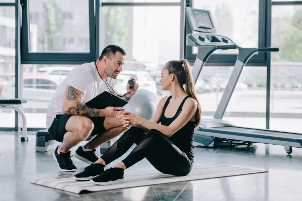 Coach sportif accompagnant une cliente lors d'une séance de remise en forme en salle