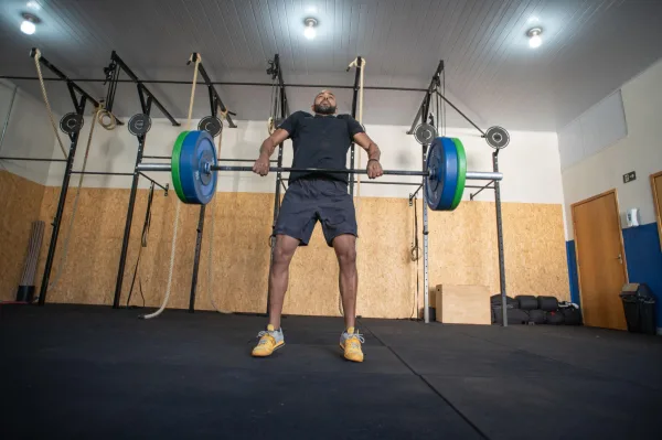 Athlète pratiquant l'haltérophilie avec une barre olympique dans une salle de CrossFit