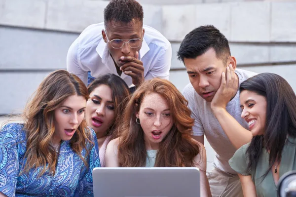 Groupe de jeunes réagissant à un contenu viral sur un ordinateur portable