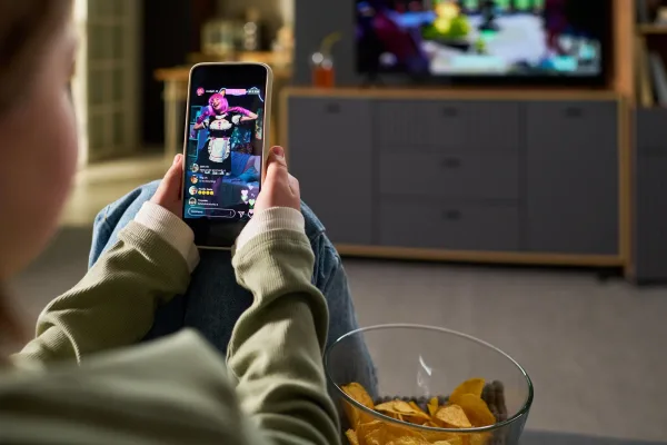 Personne regardant un live sur smartphone tout en regardant la télévision à la maison