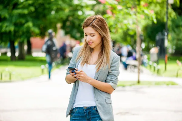 Jeune femme utilisant un smartphone dans un parc urbain