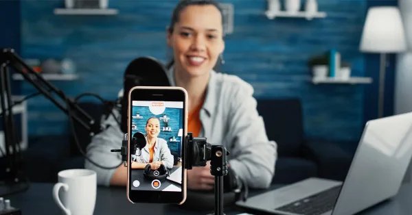 Créatrice de contenu enregistrant une vidéo avec smartphone dans un studio de podcast